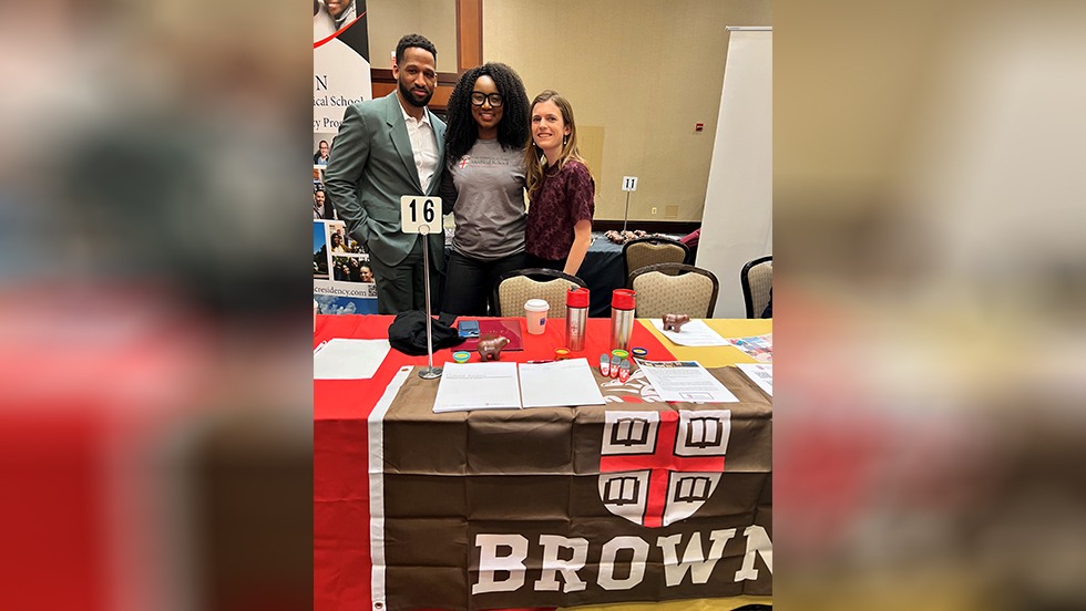 people posing for a photo in front of a Brown banner